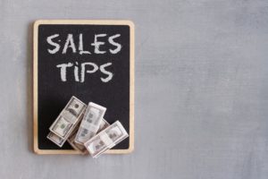 Top view image of banknotes and chalkboard with text SALES TIPS.